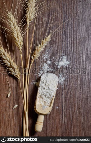 whole flour and wheat ears on wooden board