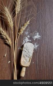 whole flour and wheat ears on wooden board
