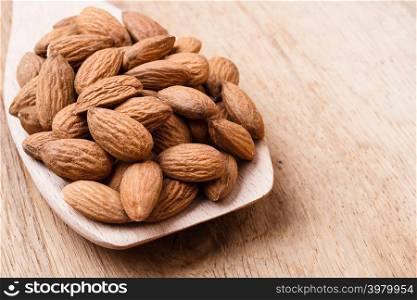 Whole food, good for health. Almonds on wooden spoon kitchen board background
