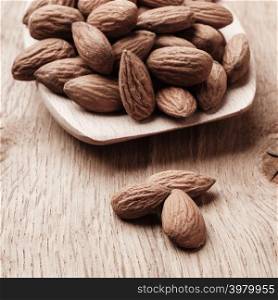 Whole food, good for health. Almonds on wooden spoon kitchen board background