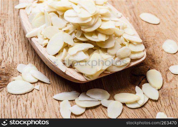 Whole food, good for health. Sliced blanched almonds on wooden spoon kitchen board background