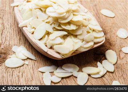 Whole food, good for health. Sliced blanched almonds on wooden spoon kitchen board background