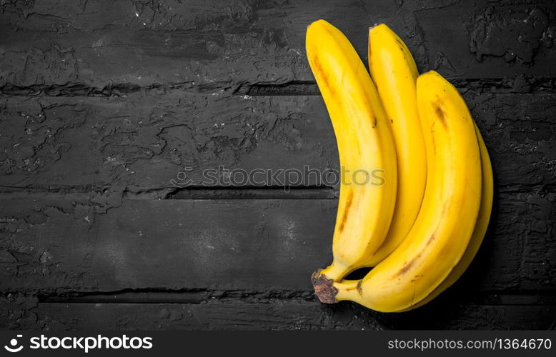 Whole fresh bananas. On black rustic background.. Whole fresh bananas.