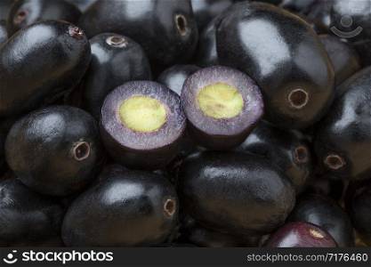 Whole fresh black Jamun berries full frame and halved ones