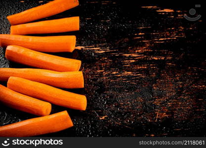 Whole fresh carrots on the table. On a rustic dark background. High quality photo. Whole fresh carrots on the table.