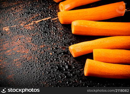 Whole fresh carrots on the table. On a rustic dark background. High quality photo. Whole fresh carrots on the table.