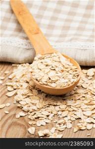 Whole grain, rolled oats with wooden spoon and homespun napkin.