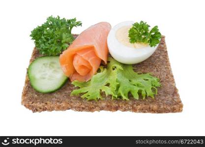 whole grain rye bread sandwich with salmon, egg and vegetables, isolated