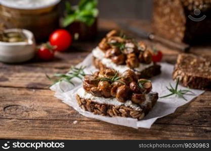 Whole grain rye bread toast with cream cheese or ricotta, mushroom and herbs on rustic wooden background.. toast with cream cheese and mushroom