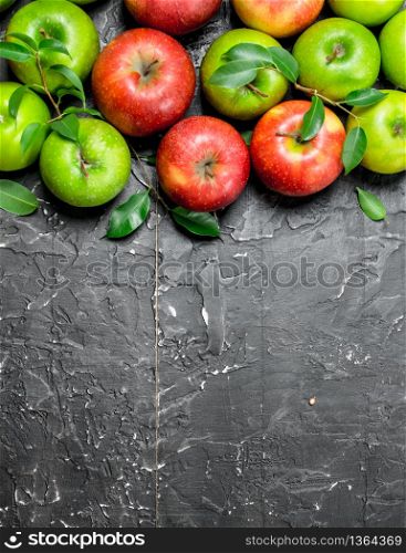 Whole green and red apples with leaves. On black rustic background.. Whole green and red apples with leaves.