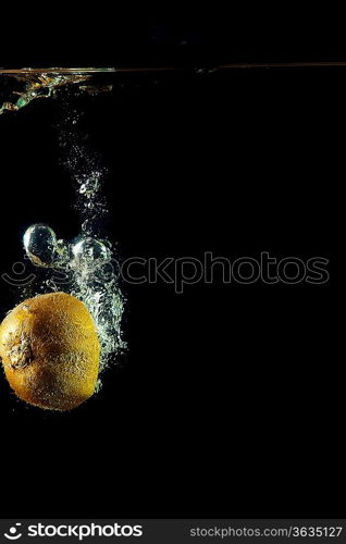 whole kiwi fruit o uder water on black background