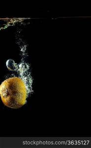 whole kiwi fruit o uder water on black background