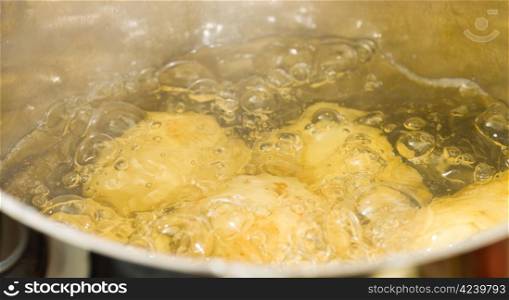 Whole potatoes boiling in cover-less stainless steel pan