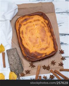 whole rectangular pie of cottage cheese and pumpkin on a white wooden table, top view