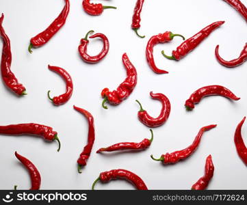 whole ripe red hot pepper scattered on a white background, fragrant spice for cooking, full frame