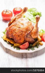 Whole Roasted Chicken on a plate with fried potatoes. The roasted chicken