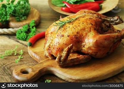 Whole roasted chicken on cutting board. Whole roasted chicken with herb on cutting board