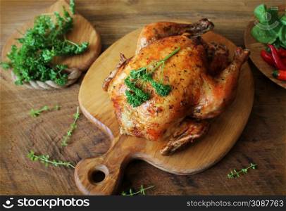 Whole roasted chicken with herb on cutting board .. Whole roasted chicken on cutting board