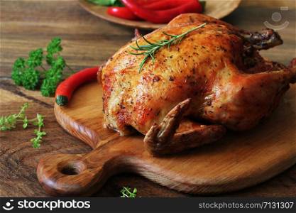 Whole roasted chicken with herb on cutting board. Whole roasted chicken on cutting board