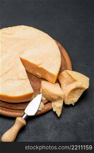 Whole round Head and pieces of parmesan or parmigiano hard cheese. Whole round Head and pieces of parmesan or parmigiano