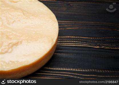 Whole round Head of parmesan or parmigiano hard cheese on dark wooden background. Whole round Head of parmesan or parmigiano hard cheese on wooden background