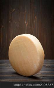 Whole round Head of parmesan or parmigiano hard cheese on dark wooden background. Whole round Head of parmesan or parmigiano hard cheese on wooden background