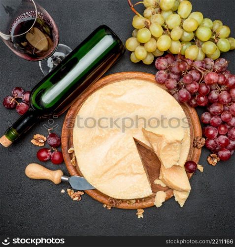 Whole round Head parmesan cheese, wine and grapeson wooden cutting board. Whole round Head parmesan cheese, wine and grapes