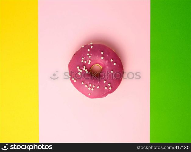 whole round red donut with sprinkles lie on a color background, top view