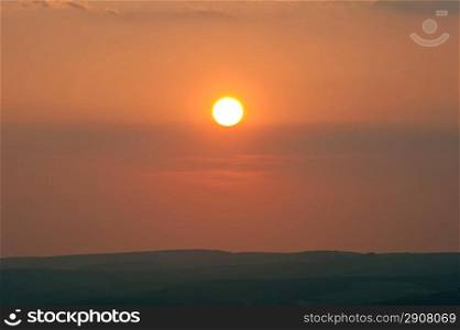 Whole sun in image setting over horizon