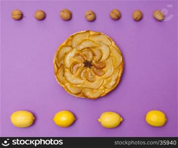 Whole tarte Tatin apple and pear tart pie with fruits on purple background with copy space