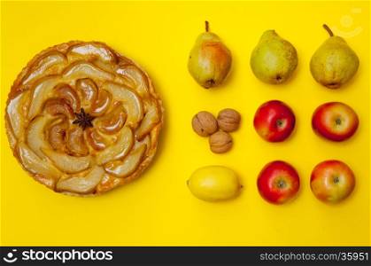 Whole tarte Tatin apple and pear tart pie with fruits on yellow background with copy space
