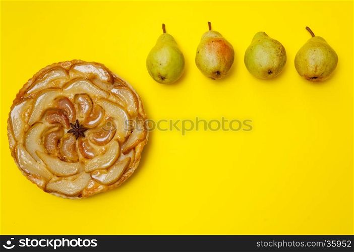 Whole tarte Tatin apple and pear tart pie with pears on yellow background with copy space