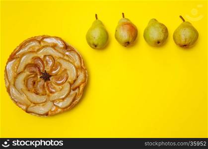 Whole tarte Tatin apple and pear tart pie with pears on yellow background with copy space
