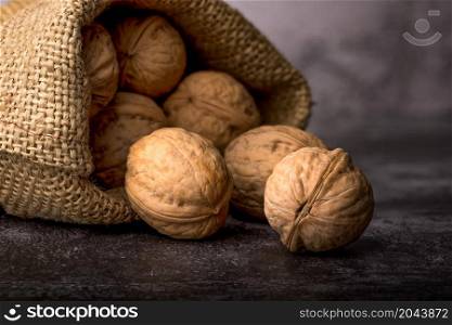 Whole walnuts in a sackcloth on a textured background. Walnuts in sack