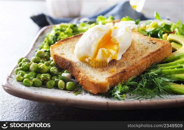 Whole wheat toasted bread with avocado, poached egg, pea on plate. Top view. Healthy diet breakfast