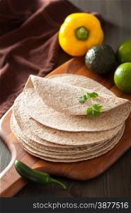 whole wheat tortillas on wooden board and vegetables