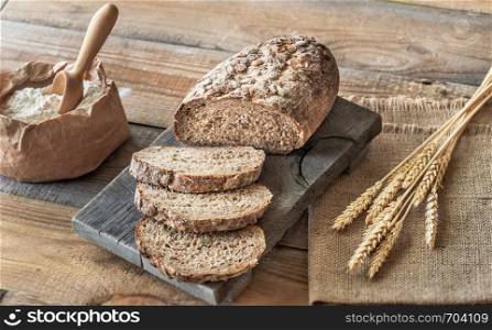 Wholegrain bread with ears of wheat on the wooden board