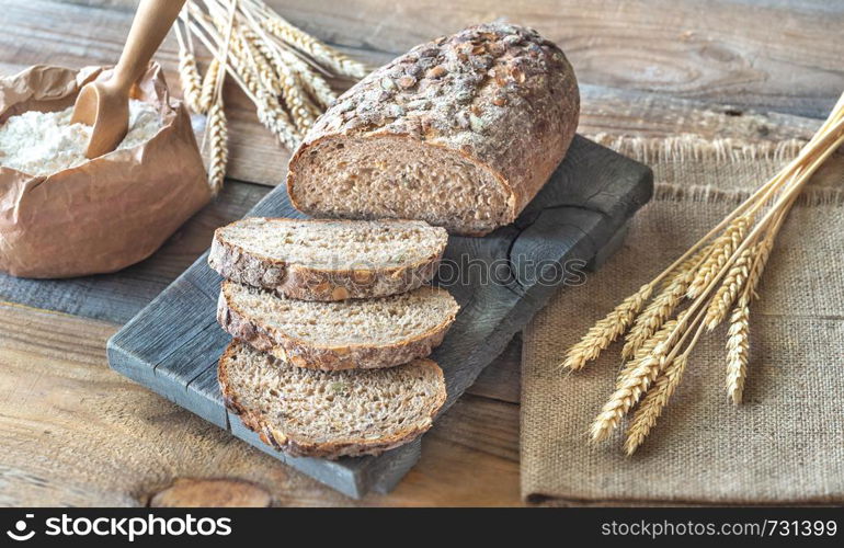 Wholegrain bread with ears of wheat on the wooden board