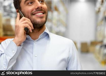 wholesale, logistic business and people concept - close up of smiling businessman calling on smartphone at warehouse. businessman calling on smartphone at warehouse