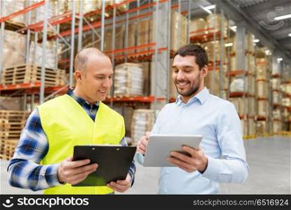 wholesale, logistic business and people concept - warehouse worker and businessman with clipboard and tablet pc computer. worker and businessman with tablet pc at warehouse. worker and businessman with tablet pc at warehouse