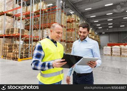 wholesale, logistic business and people concept - warehouse worker and businessman with clipboard and tablet pc computer. worker and businessman with tablet pc at warehouse