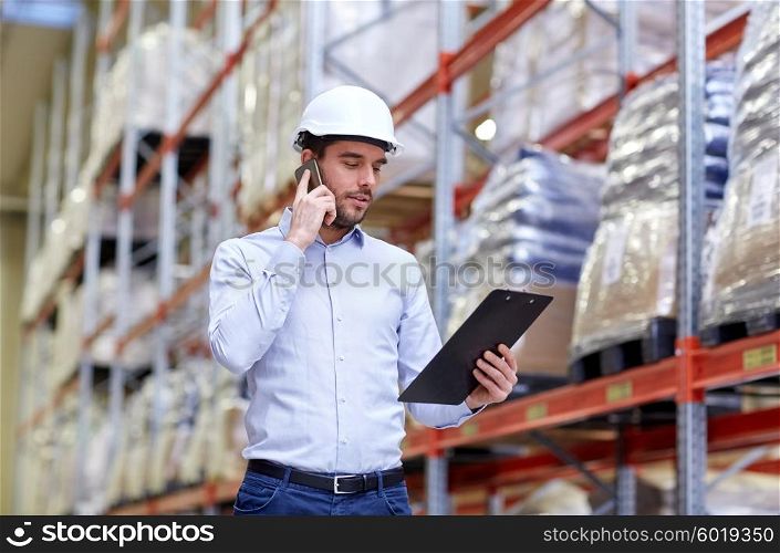 wholesale, logistic, business, export and people concept - businessman with clipboard calling on smartphone at warehouse