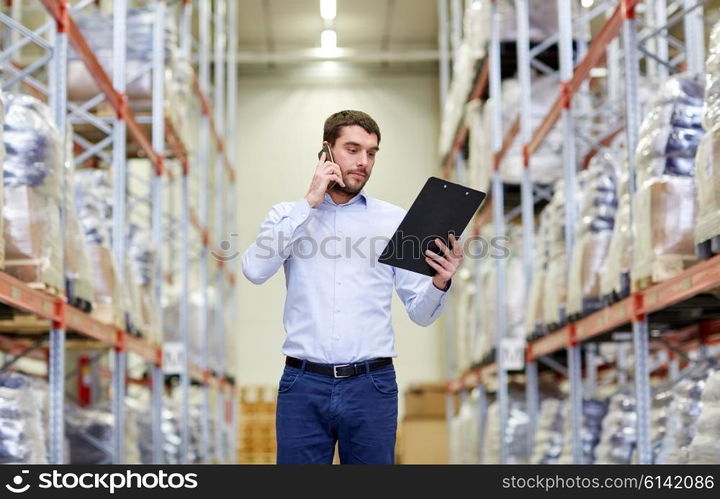 wholesale, logistic, business, export and people concept - businessman with clipboard calling on smartphone at warehouse