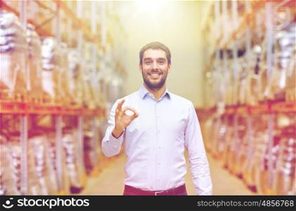 wholesale, logistic, business, export and people concept - happy man at warehouse showing ok gesture