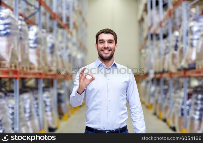 wholesale, logistic, business, export and people concept - happy man at warehouse showing ok gesture