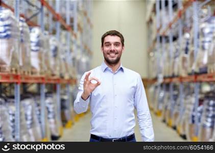 wholesale, logistic, business, export and people concept - happy man at warehouse showing ok gesture