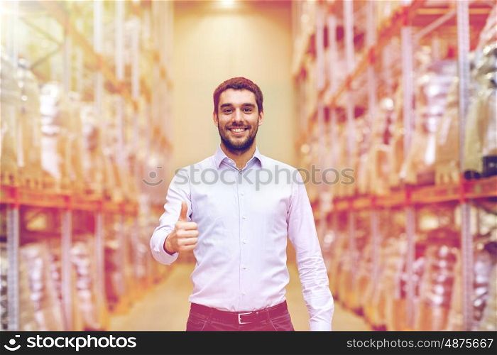 wholesale, logistic, business, export and people concept - happy man at warehouse showing thumbs up gesture