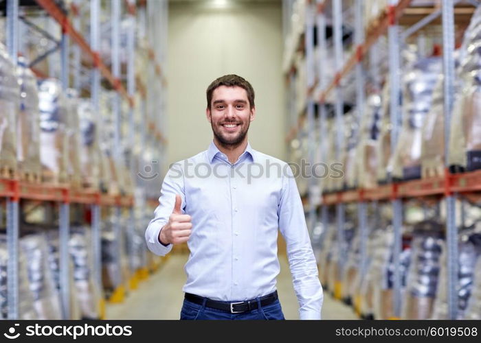 wholesale, logistic, business, export and people concept - happy man at warehouse showing thumbs up gesture