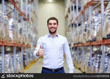 wholesale, logistic, business, export and people concept - happy man at warehouse showing thumbs up gesture