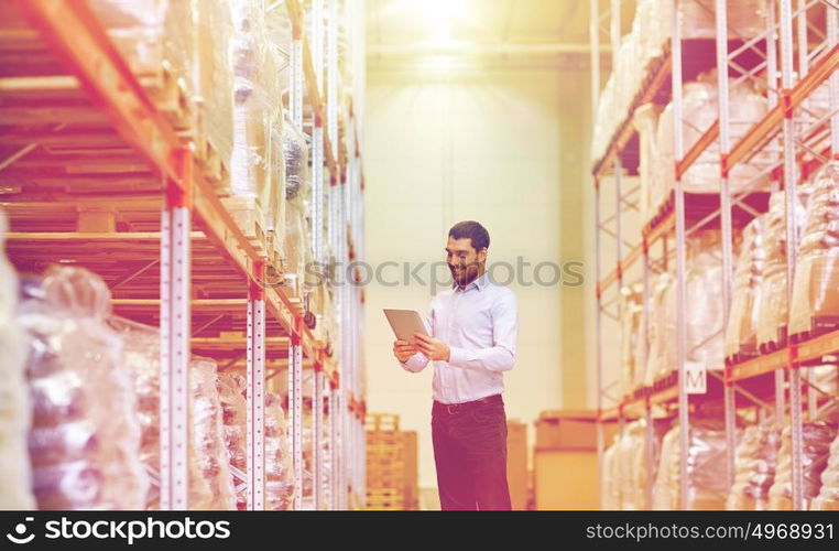 wholesale, logistic, business, export and people concept - happy man or manager with tablet pc computer checking goods at warehouse. happy businessman with tablet pc at warehouse